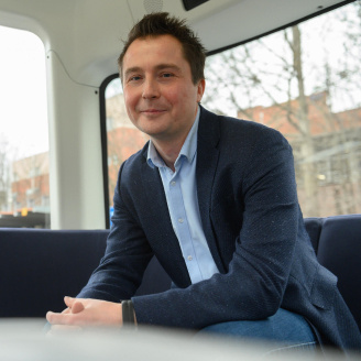 A picture of Harri Santamala smiling to the camera while wearing a navy blue jacket and a blue collar shirt with jeans.